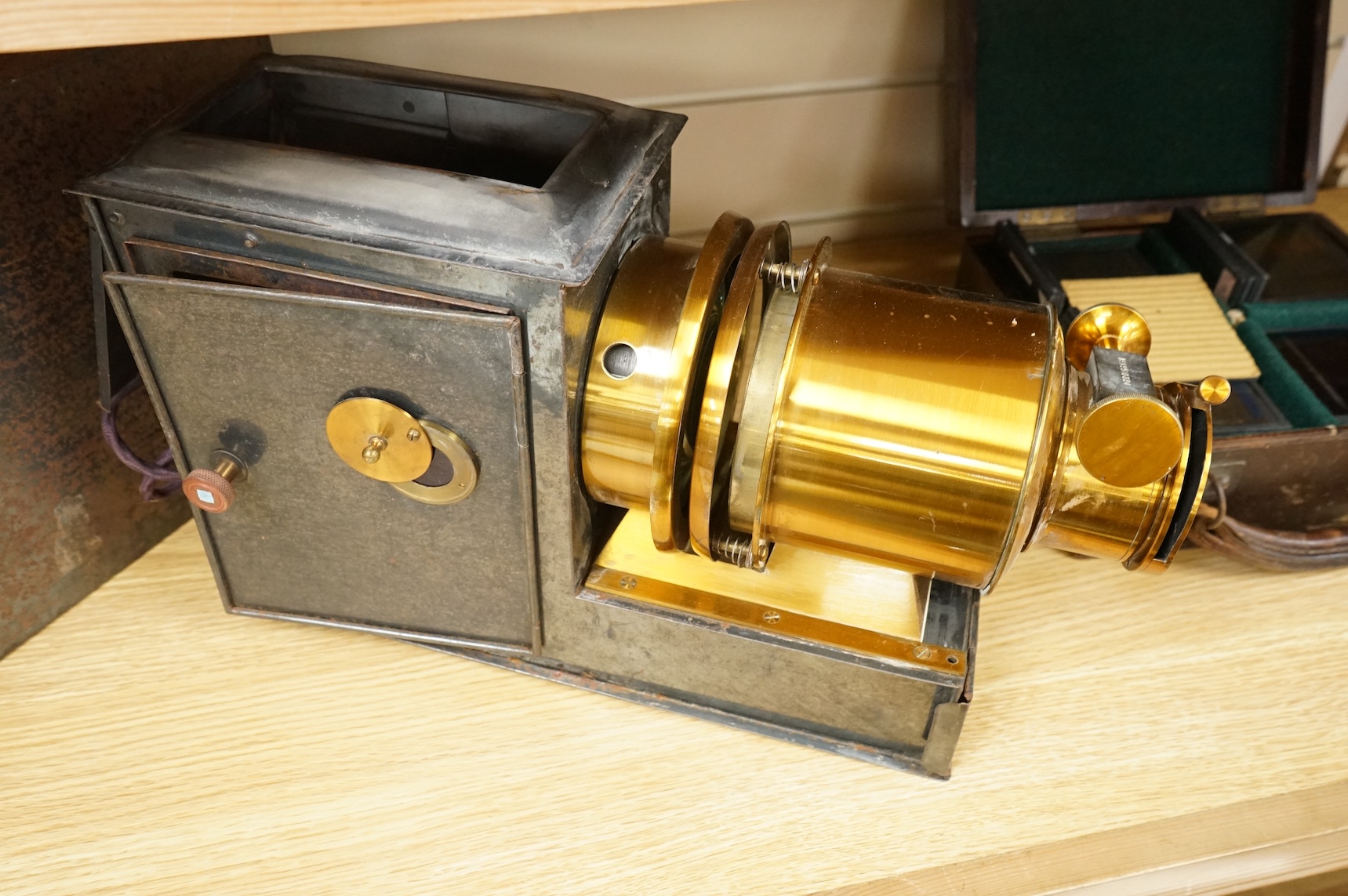 A tinplate and brass magic lantern, converted to an electric lamp and missing the original chimney, in a tin case, together with a case of slides, mostly biblical related.